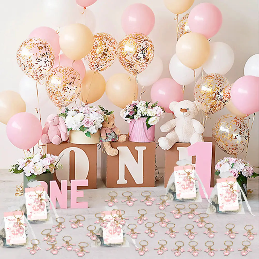 Des ballons confettis rose et or complètent les porte-clés de baby shower à empreintes de bébé comme décorations festives
