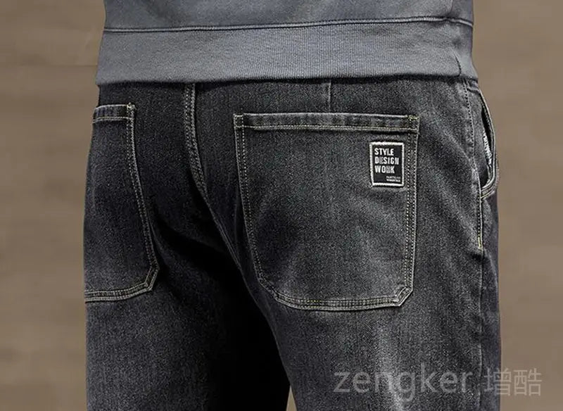 Plus size elastic waist loose straight jeans in dark-wash denim with a subtle faded texture and a black rectangular patch on the back pocket shown from the back side.