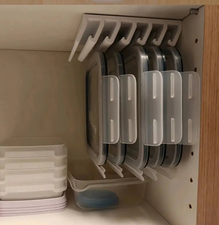 Boîtes de rangement alimentaires en plastique transparent avec des couvercles transparents et des poignées blanches, empilées avec soin dans un porte-couvercles peu encombrant pour un rangement efficace des couvercles.