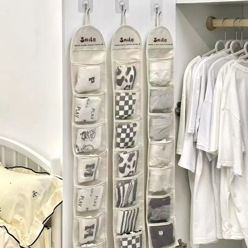 beiger hängender Kleiderschrank-Organizer mit Mesh-Taschenspeicherbeutel, der drei Stoff-Socken-Organizer mit mehreren Fächern umfasst, in denen verschiedene Socken mit unterschiedlichen Mustern aufbewahrt werden