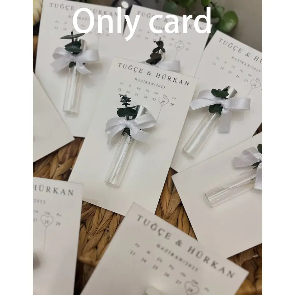 carte blanche avec un texte imprimé noir comportant une petite fiole en verre transparent fixée au moyen d’un ruban argenté et ornée d’une touche d’ornement vert foncé à feuilles, pour une carte cadeau de parfum de mariage personnalisée, faveur personnalisée