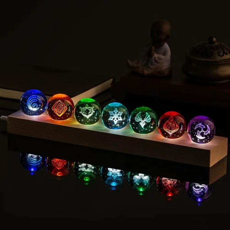 Sept sphères de verre translucides et illuminées, avec des symboles de type chakra lumineux dans des couleurs arc-en-ciel, disposées sur une base en bois, comme produits finis de la boule de cristal de Genshin Impact.