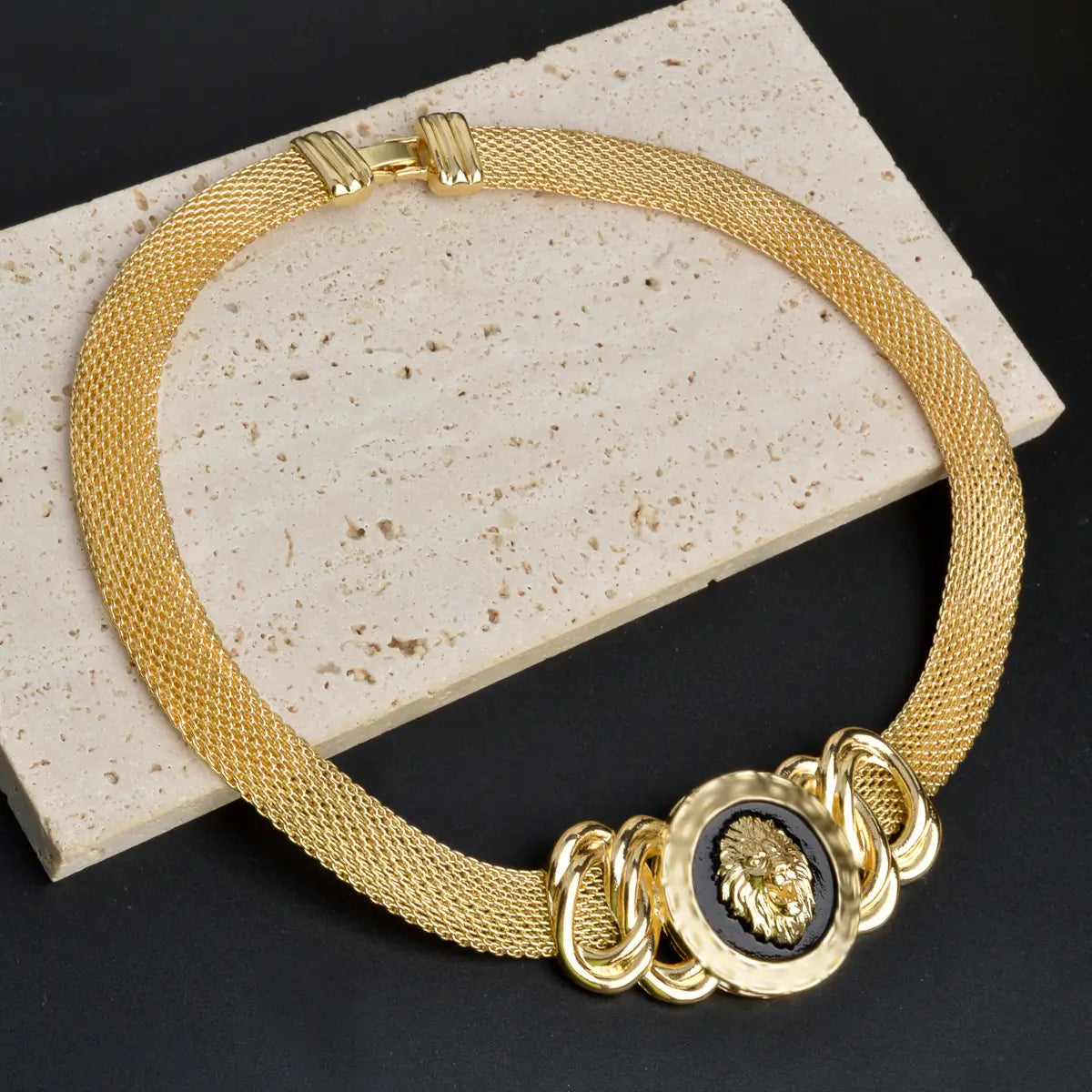Juego de joyería de león de oro de Dubái de 18 quilates que presenta un collar de malla dorada con un medallón central con cabeza de león sobre un fondo de esmalte negro y eslabones ornamentales de cadena dorada.