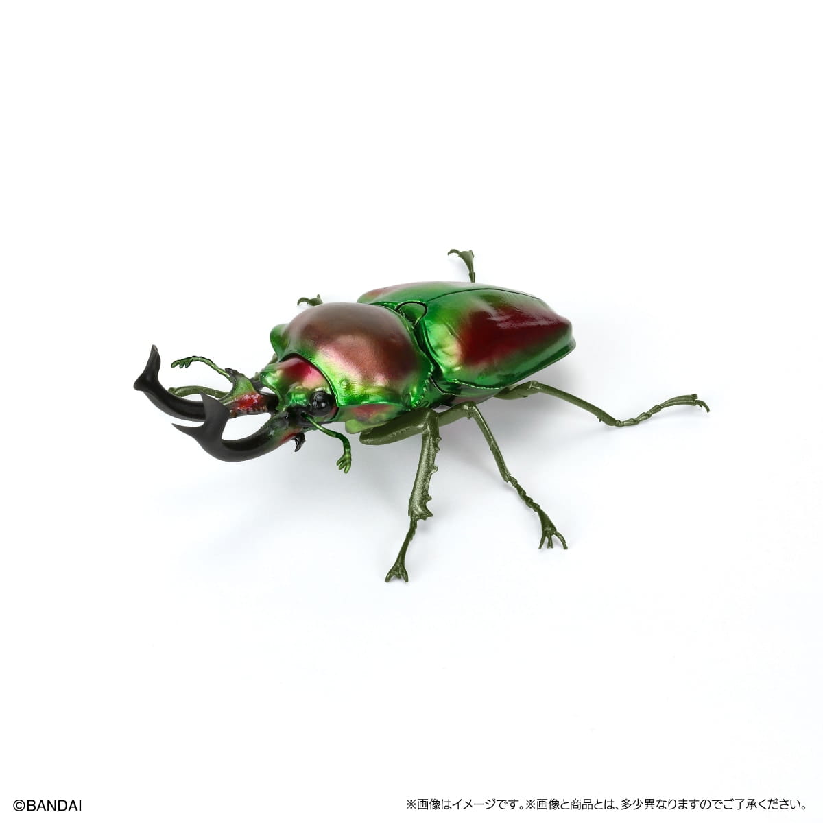 バンダイの、光沢のある虹色の緑と赤のカブトムシ(?)の置物フィギュアを特徴としたノコギリクワガタ完成品モデル玩具で、黒い角のような大あごを備えています。