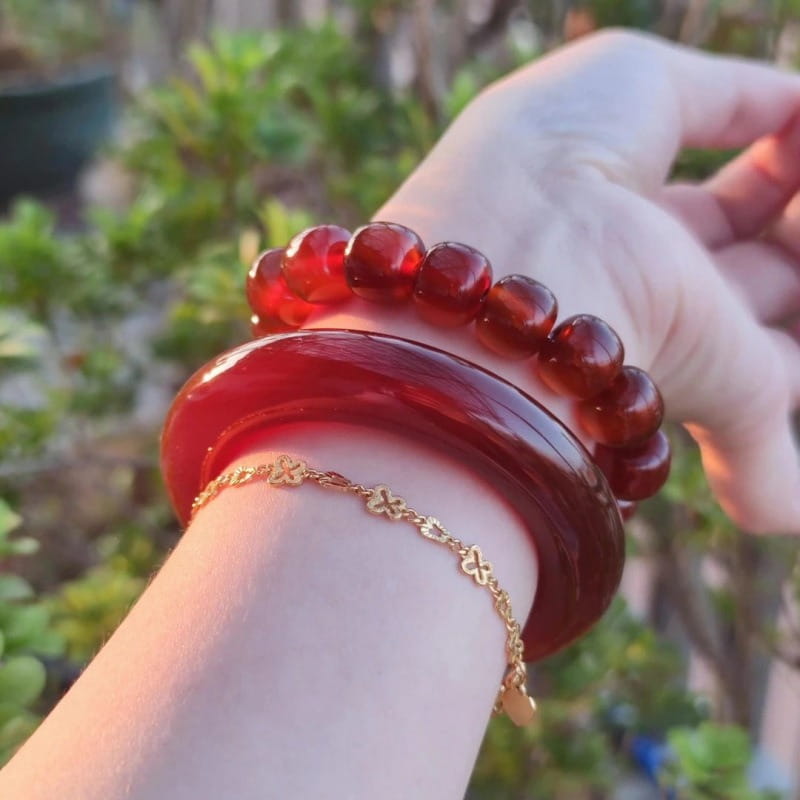 A glossy deep red jade bangle bracelet for women in classic round style worn on a wrist.