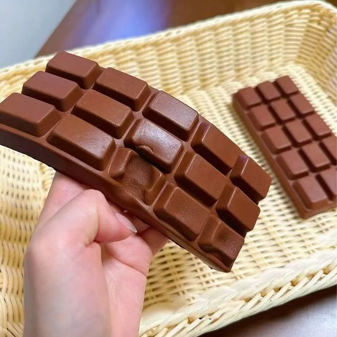 juguete exprimible en forma de tableta de chocolate marrón oscuro brillante con un diseño clásico segmentado para aliviar el estrés y favorecer la relajación