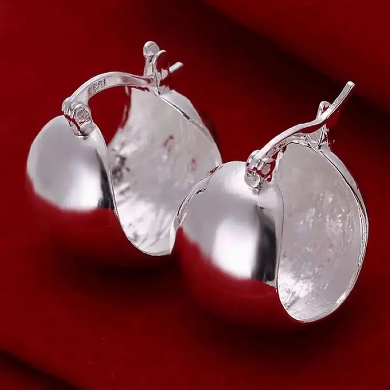 Boucles d’oreilles créoles minimalistes en argent sterling 925 façonnées comme des pommes argentées brillantes, avec une finition métallique polie et des détails délicats de tige.