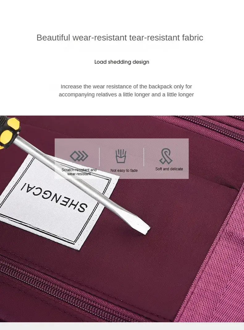 Un sac duffel roulant en tissu bordeaux à grande capacité, conçu comme sac à dos de voyage, avec une étiquette shengcai blanche et des coutures renforcées.