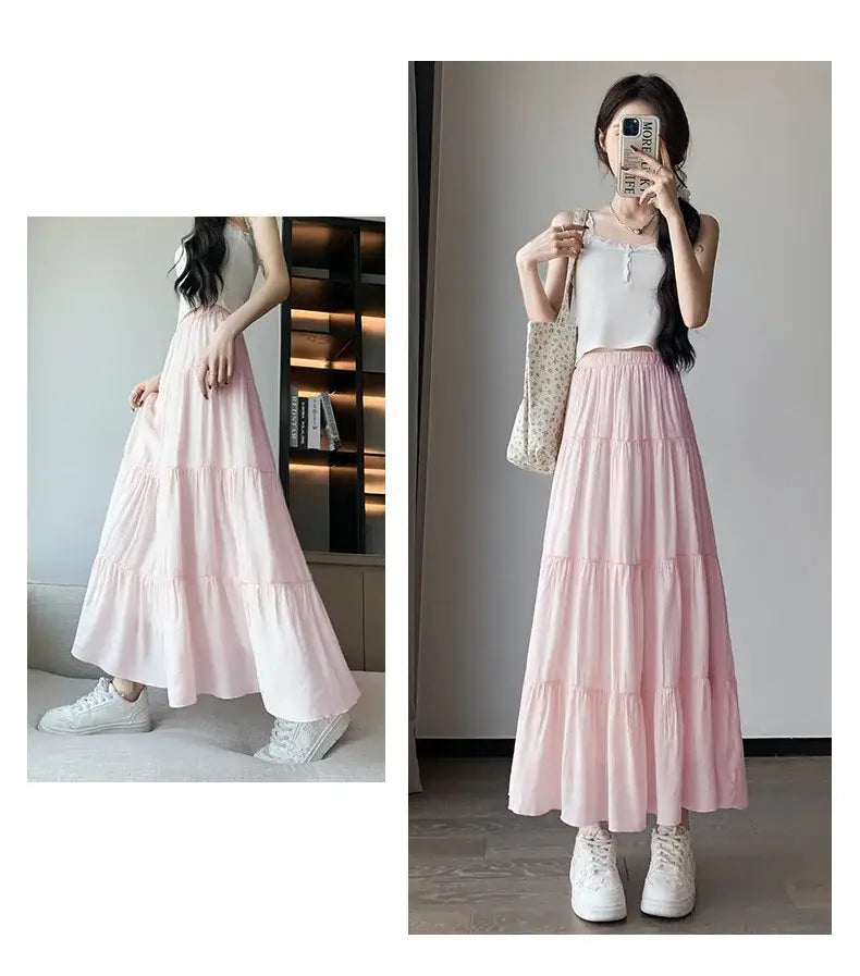 Jupe longue maxi plissée à volants superposés blanche en rose pastel doux, avec un tissu fluide et léger et des ourlets à volants délicats.