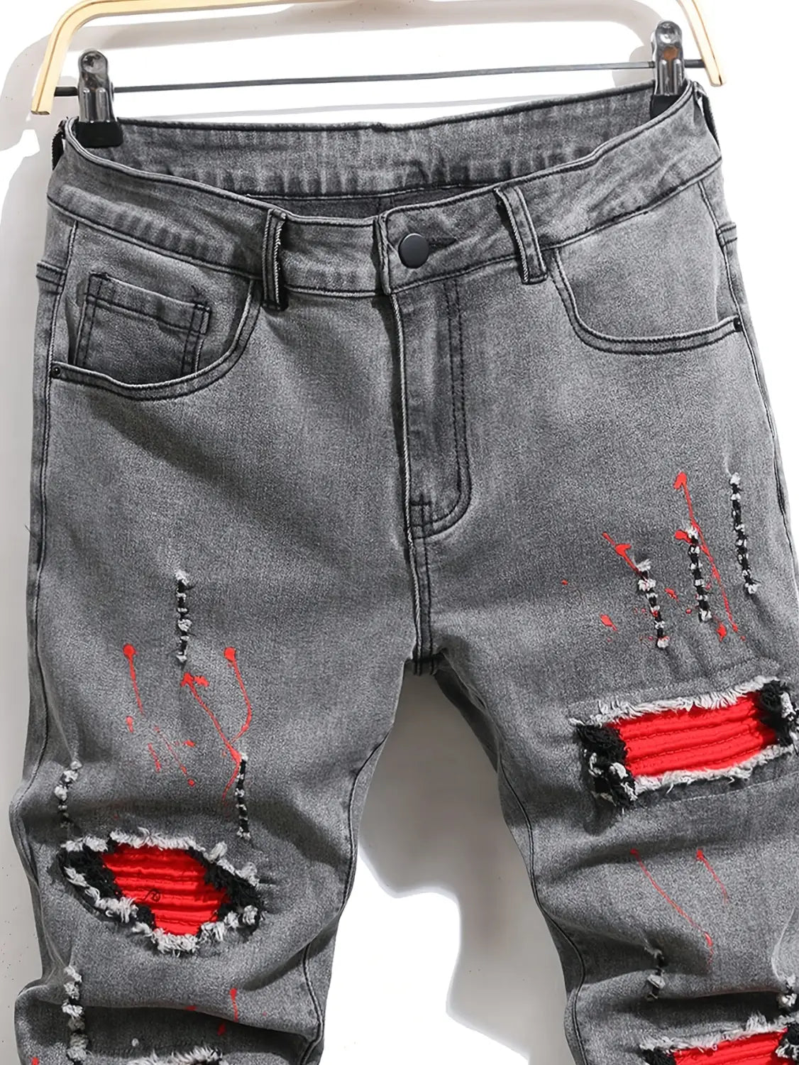 Herren-Ripped-Skinny-Bikerjeans in abgenutztem grauem Denim mit kräftigen roten Stoffpatches und schwarz-weiß gestickten Akzenten für den Streetwear-Stil.