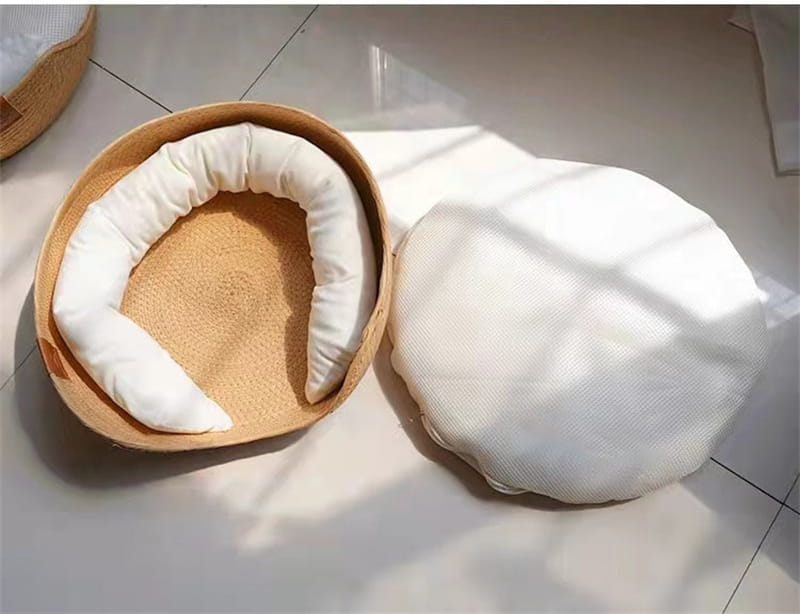 A cozy round cat bed sleeping bag made of woven wicker paper rope with plush white cushioning for comfortable resting.