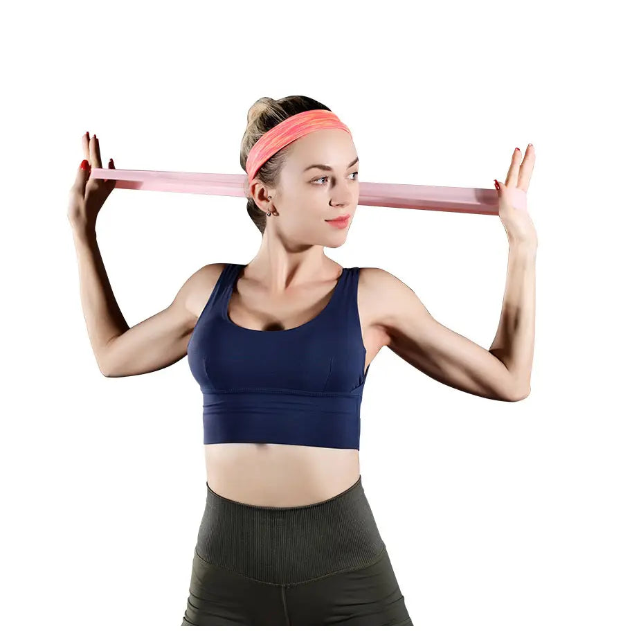 A woman holding a pink resistance band horizontally demonstrating the purple resistance bands set for home fitness use.