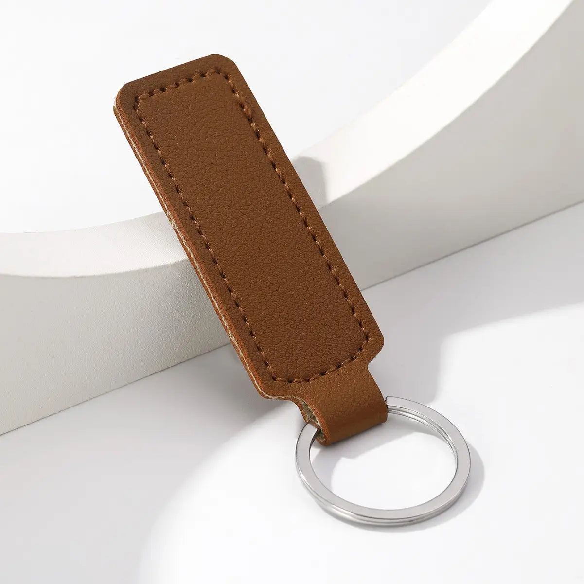 Brown leather minimalist strip keychain with a silver metal ring for holding car keys.
