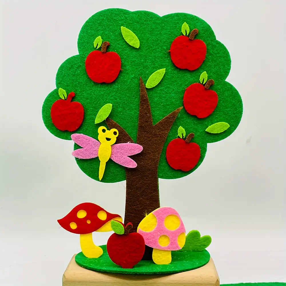 kit de manualidades estacionales de árbol de fieltro tipo diy que incluye un árbol de fieltro colorido con tronco marrón, vegetación verde y manzanas rojas, acompañado de una libélula rosa y setas moteadas