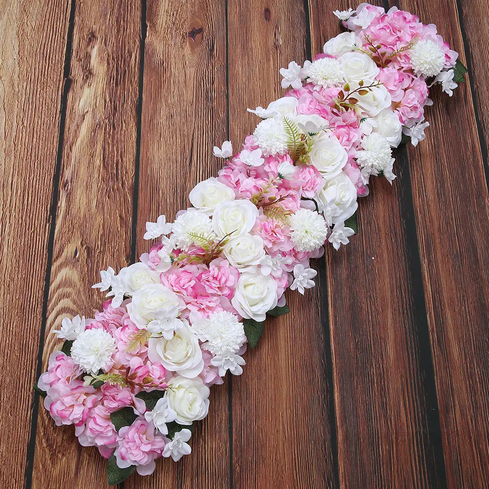 Composition de fleurs de sol pour mariage de rose blanche, présentant une guirlande florale décorative d’roses artificielles roses et blanches, d’hortensias et de petites fleurs, rehaussées de feuilles vertes.