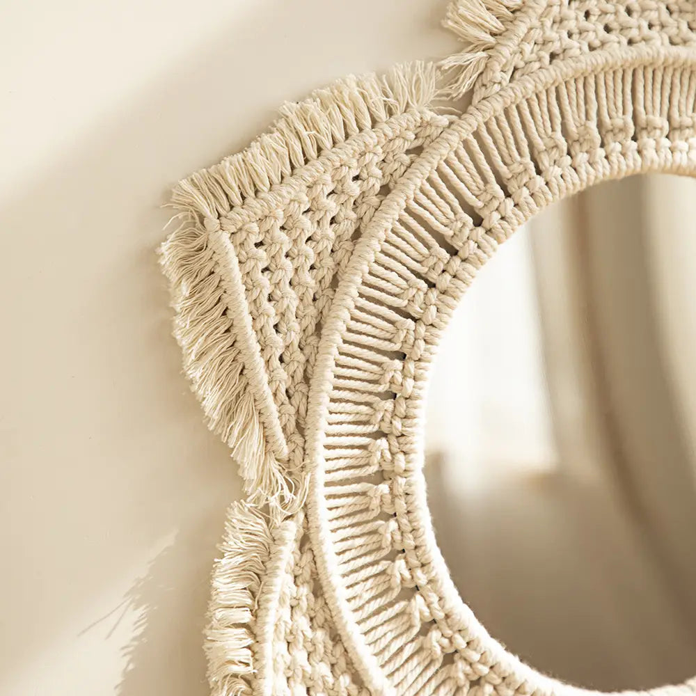 Cream-colored macrame wall mirror with intricate woven patterns and fringed edges for living room home decor.