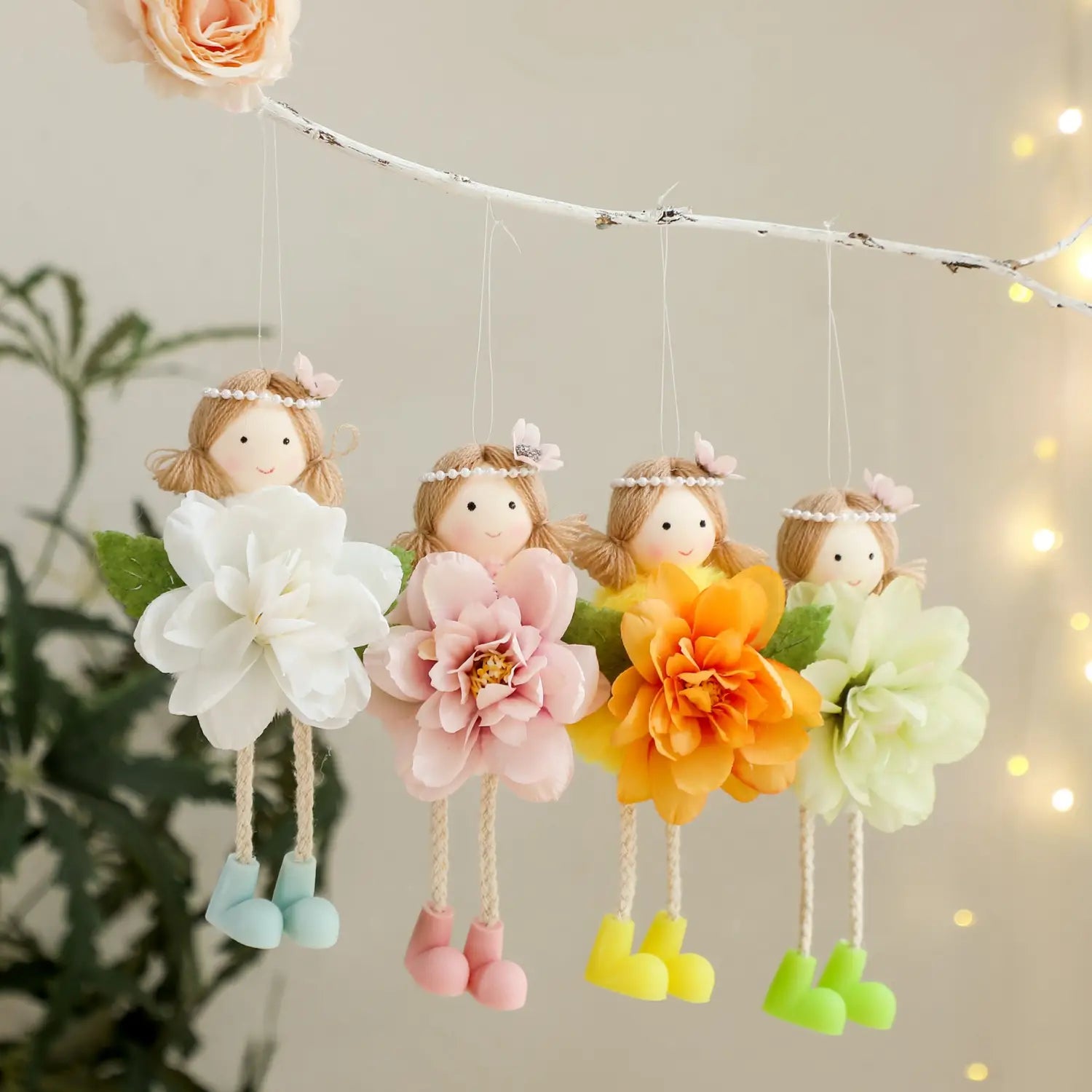 easter fairy hanging ornaments 4-pack featuring four soft fabric face fairies with pearl headbands dressed in oversized artificial flowers in white pink orange and light green with colorful plastic boots.