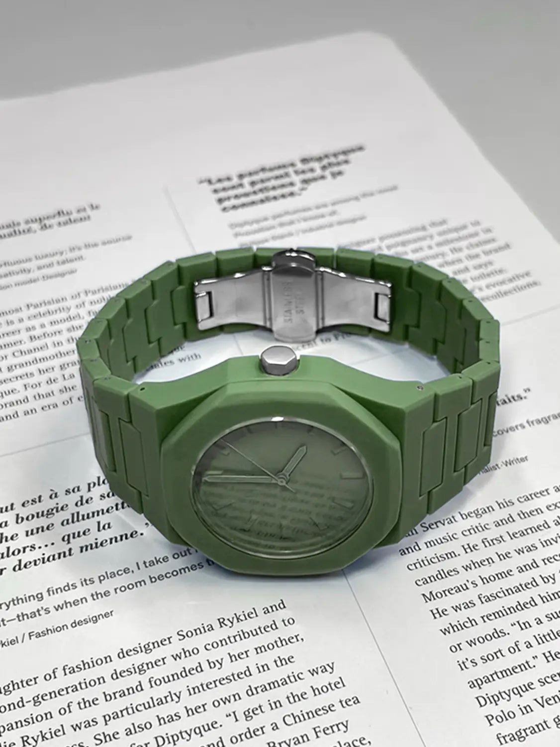 Herrenarmbanduhr Tomi im minimalistischen Design aus weißer Keramik mit einem olivgrünen Silikonarmband, einem silberfarben wirkenden Metallschließenverschluss sowie Lünette, und einem dazu passenden Zifferblatt mit minimalistischen Stundenmarkierungen.