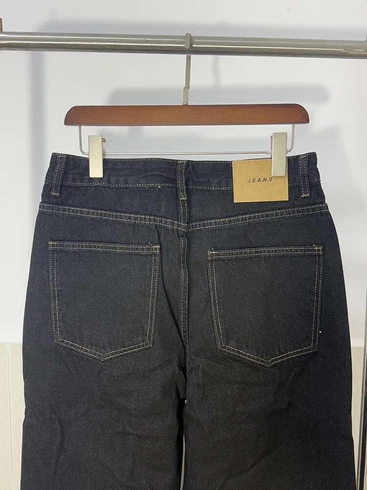 Iefb men black vintage wide leg jeans in dark-wash denim with light stitching and a beige label hanging on a wooden hanger.