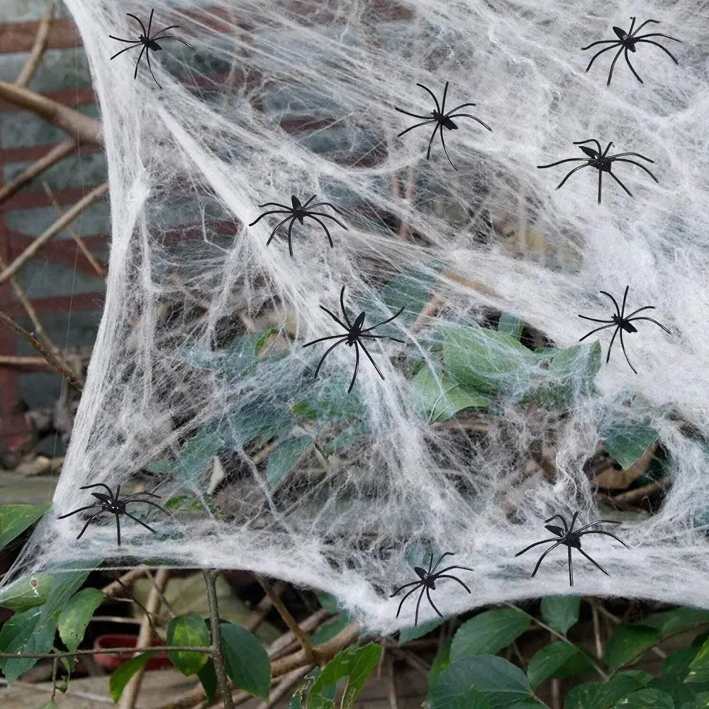 a decorative white spiderweb made of fabric with multiple black plastic spiders scattered across it designed as horror props halloween for a halloween party decoration