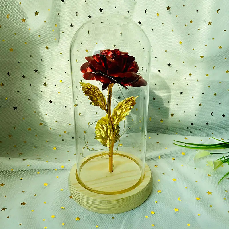 Geschenk „Eternal Gold Rose Glass Dome LED Light“, mit einer roten und goldenen konservierten Rose, die in einer klaren Glaskuppel auf einem hellen Holzsockel zur Geltung gebracht wird.