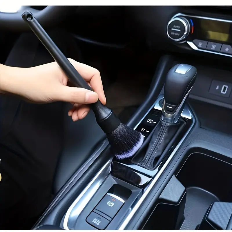 Detailreinigungsbürste für den Innenraum eines schwarzen Fahrzeugs mit dichten weichen Borsten und einem eleganten Griff für eine präzise Reinigung.