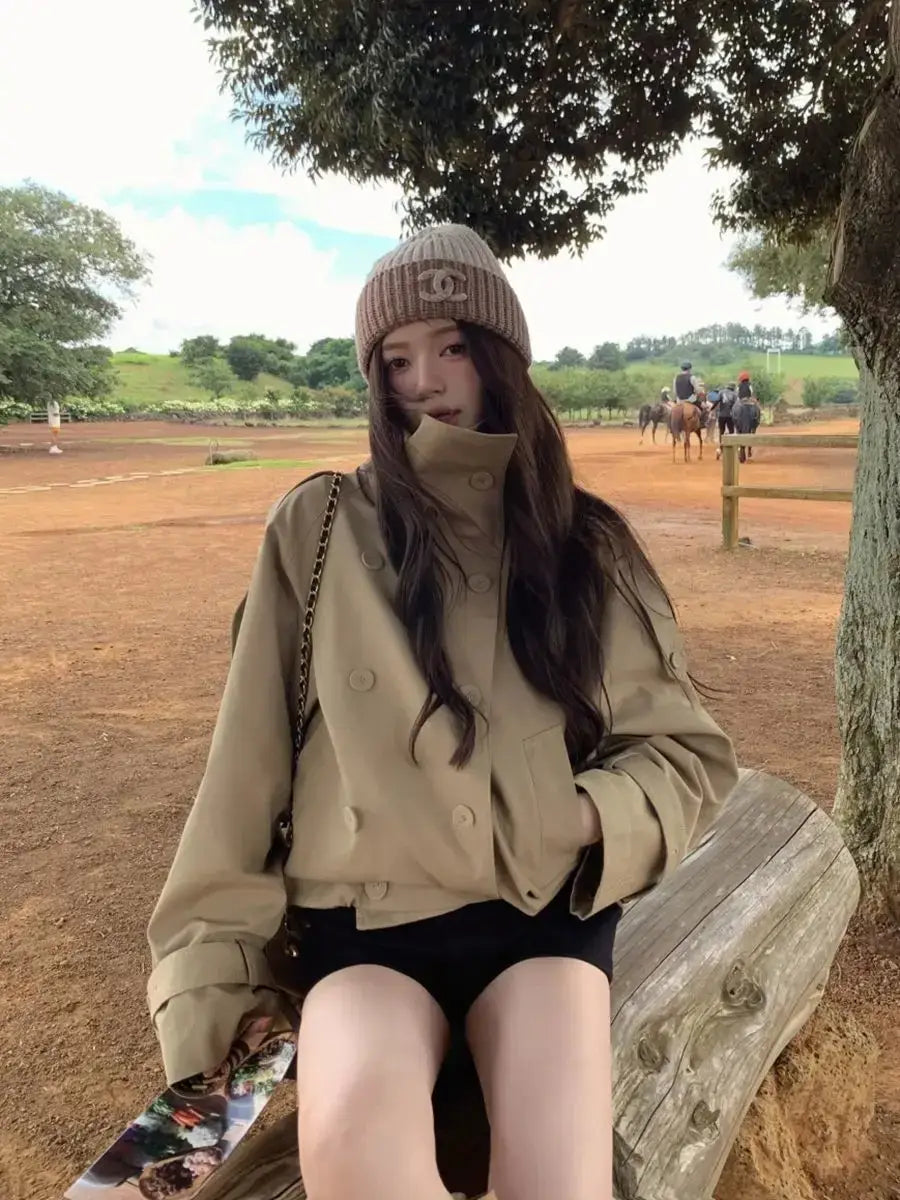 Beige double-breasted Korean style trench coat with high collar and buttoned cuffs designed as a utility jacket.