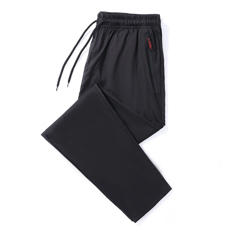 Joggers casuales ajustados para hombre en tejido deportivo negro, con cintura elástica y cordón, que presenta una sutil presilla roja de la cremallera en el bolsillo lateral.