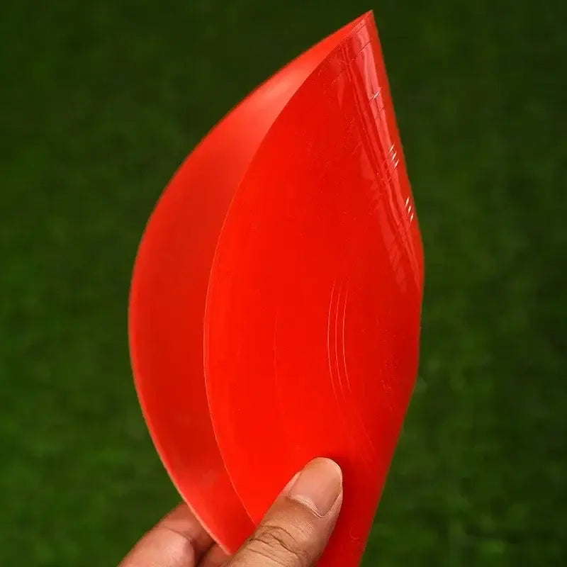 Ein leuchtend roter, glänzender Kunststoff-Kegel in Blattform für Agility-Training, in der Hand gehalten.