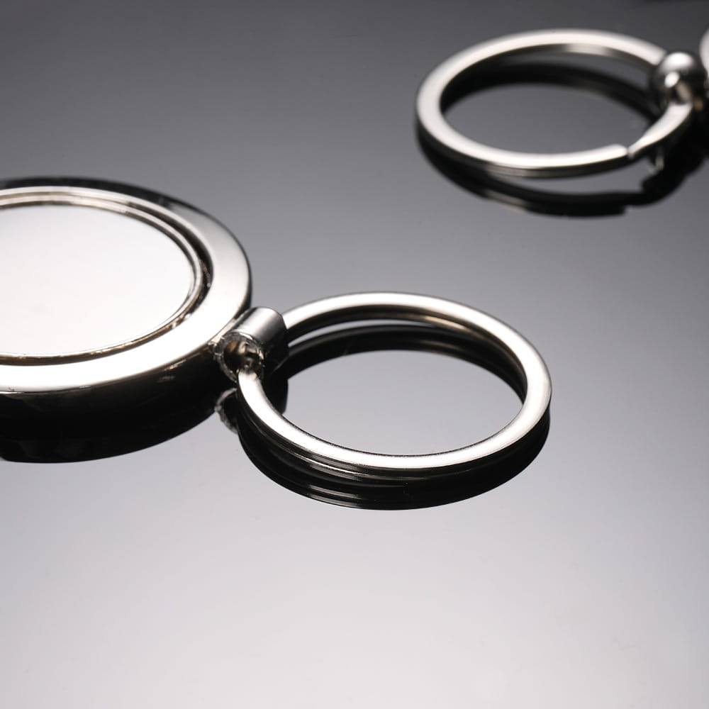 Silver metallic rotating circle keychain featuring a circular flat disc attached to a ring via a hinge mechanism designed as a gift accessory.