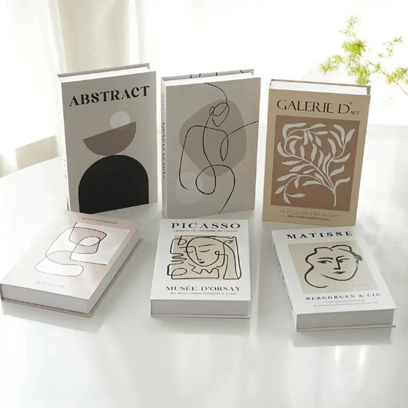 Set of six minimalist art-themed decorative fake books with abstract modernist designs in neutral beige cream black and brown matte-finished covers for coffee table home decor.