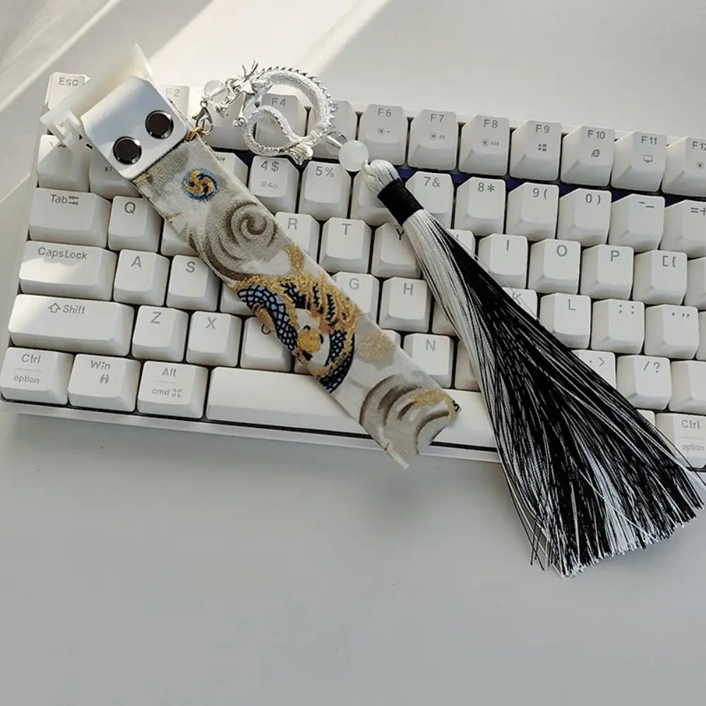 Sangle personnalisée pour le modèle Ribbon Dragon du clavier Wooting, comprenant un porte-clés décoratif sur le thème du dragon, un fermoir métallique argenté et un pompon noir et blanc.