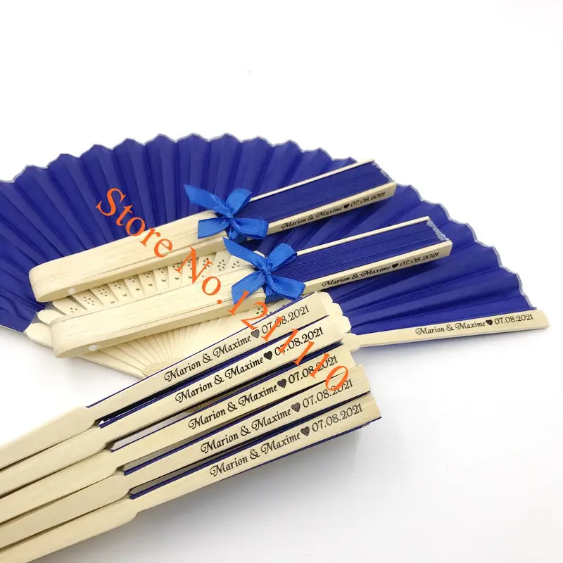 Blue and cream-colored folding bamboo silk hand fans with personalized engraving for a wedding date custom wedding favors.