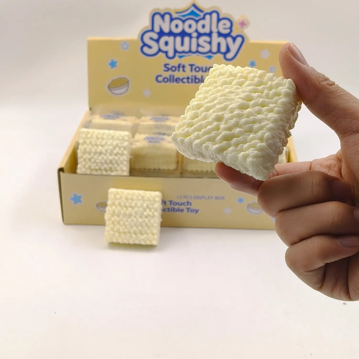 a creamy white noodle-shaped instant noodle squishy toy with a textured knitted-like surface designed for stress relief and building block play.