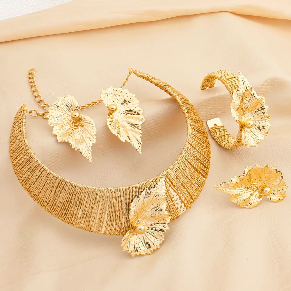 Parure de bijoux en perles et feuilles d’or, comprenant un collier statement, des boucles d’oreilles assorties et un bracelet, avec des textures tissées complexes et des accents de perles dans un ton doré.