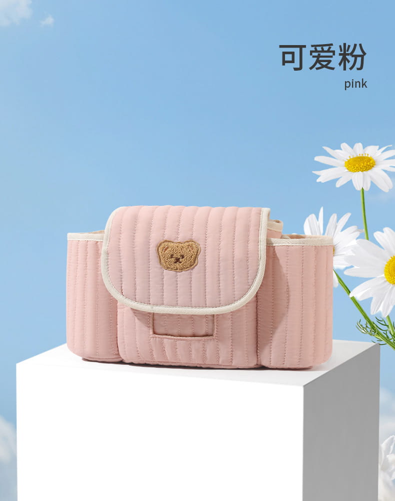 Rosa gepolsterter Babytragebeutel mit einer beigen Bären-Applikation, dargestellt auf einem Organizer-Beutel für den Kinderwagen, entworfen für eine praktische Aufbewahrung und Organisation.