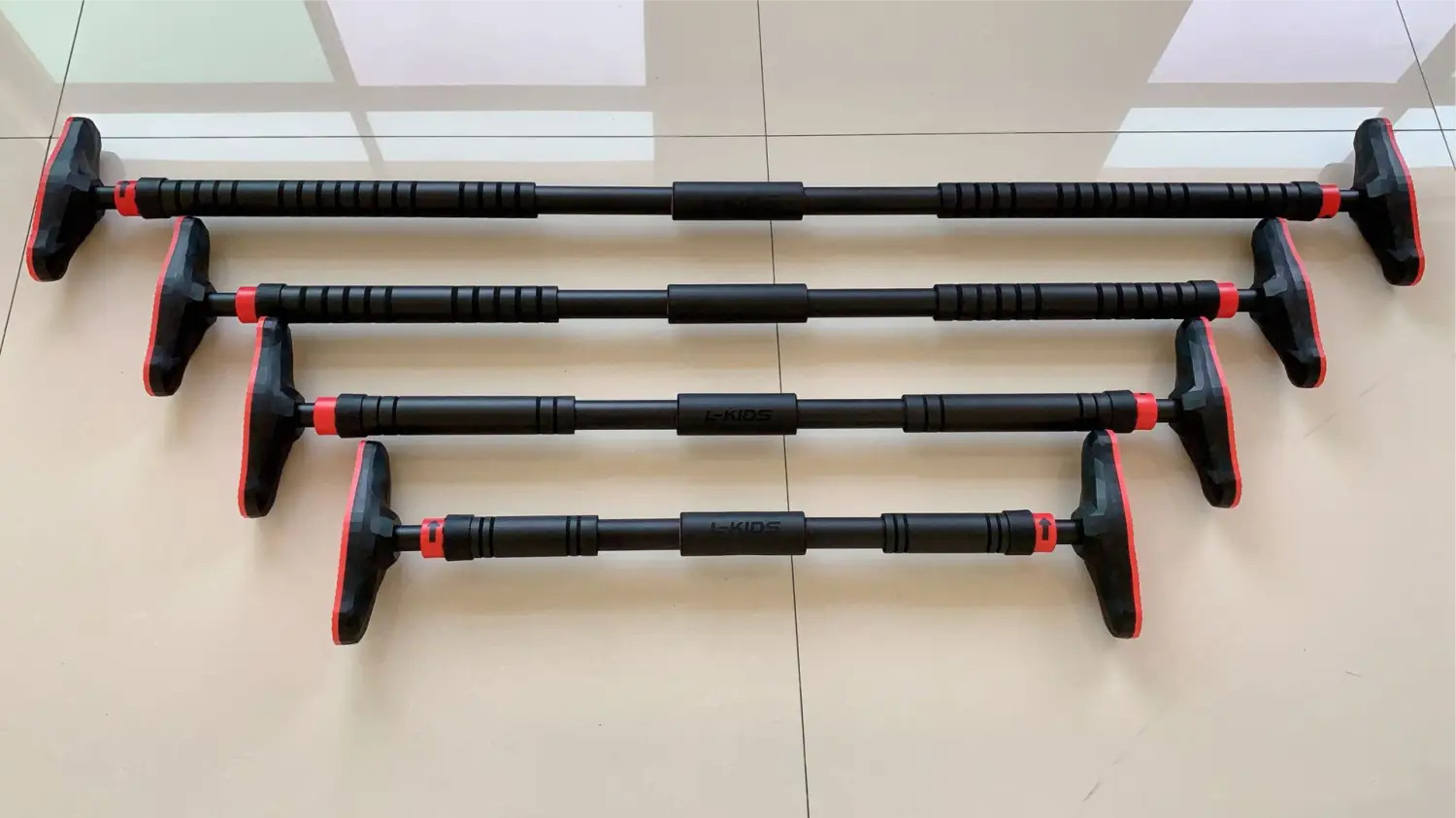 Barre de traction pour porte ajustable pour le fitness à domicile, noire et rouge, avec prises texturées et construction métallique robuste.