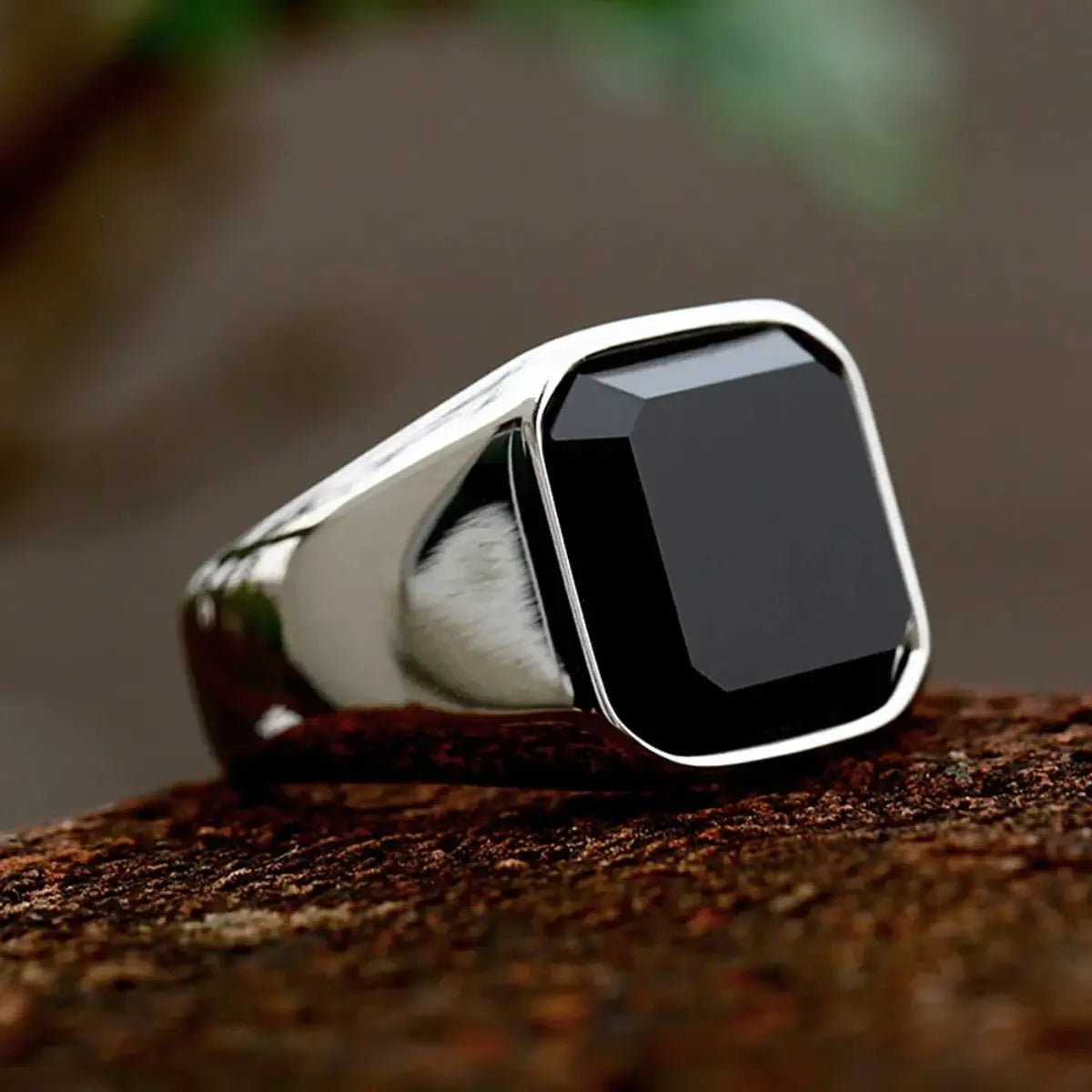 Ein eleganter schwarzer Onyx-Signetring in Silber für Damen und Herren, mit einem markanten quadratisch geschliffenen schwarzen Onyx-Stein, der in einem polierten Metallband eingesetzt ist.