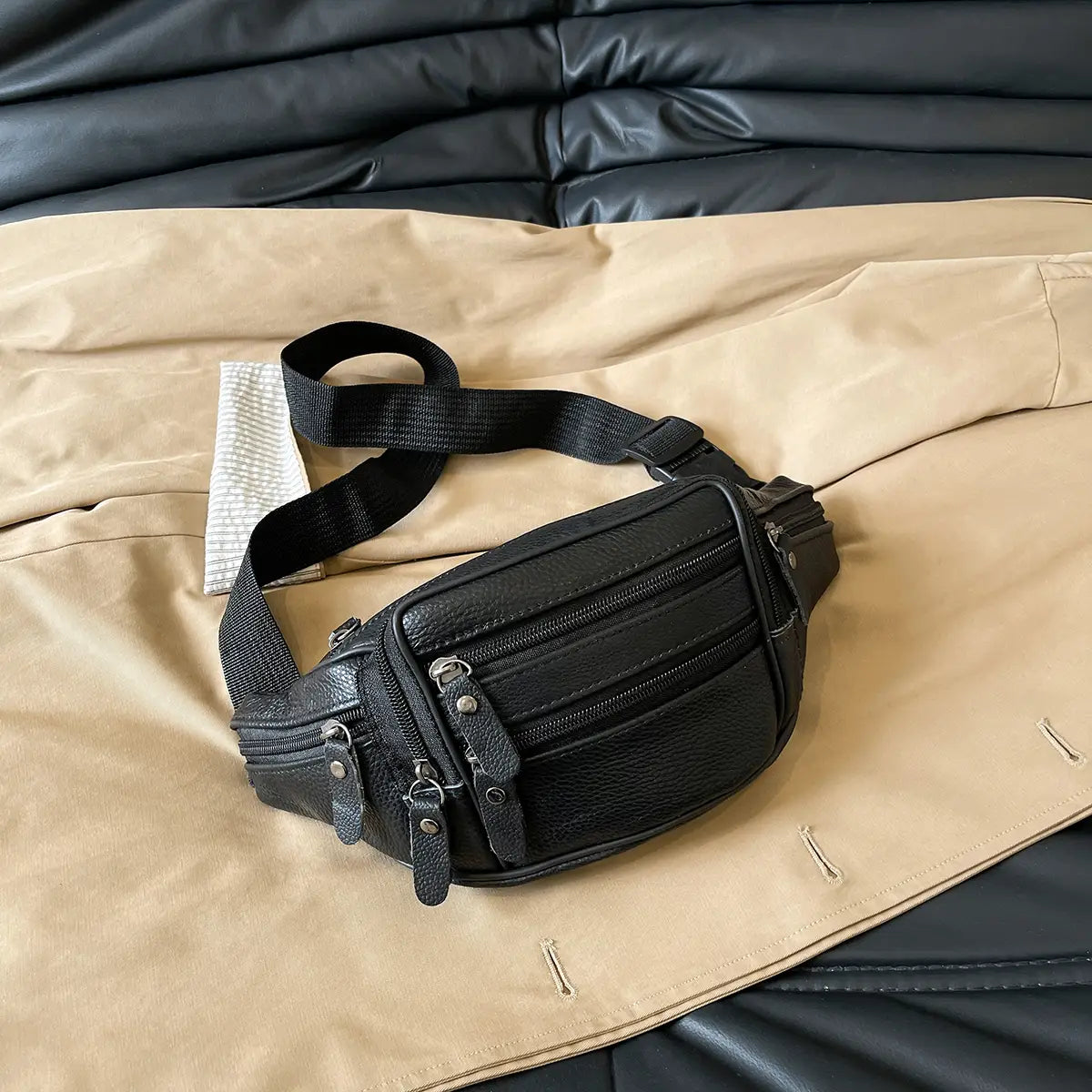 Schwarze Gürteltasche aus echtem Leder mit mehreren Reißverschlüssen und einem robusten, verstellbaren Riemen, konzipiert als Crossbody-Bauchtasche.