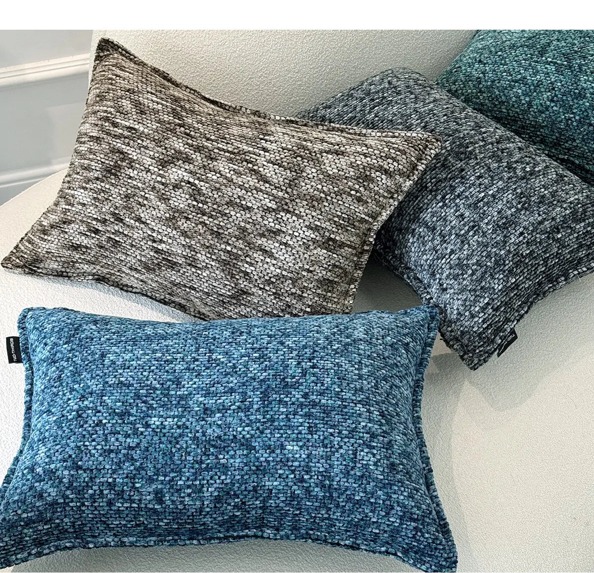 La housse de coussin d’appoint en chenille présente un tissu tissé texturé aux tons bleu gris atténués et bleu-vert pour un usage décoratif.