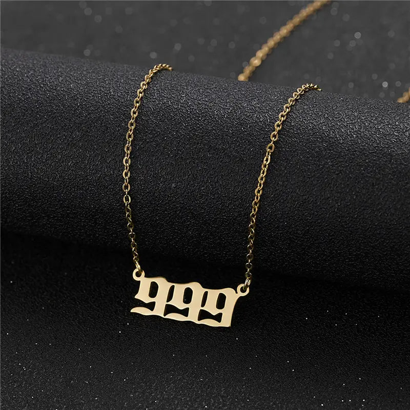Gold angel number 7 necklace featuring a gold-toned chain with a sleek gothic-style 999 pendant.