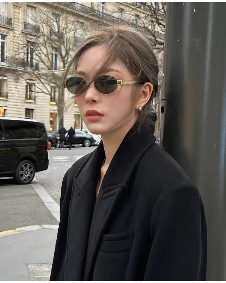 Un par de gafas de sol ovaladas para mujer y hombre con lentes verde oscuro y una montura metálica con acabado dorado.