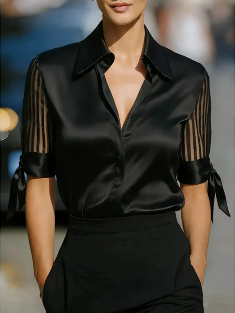 Chemisier en satin noir à poignets boutonnés avec nœud, avec des manches transparentes rayées rouges et des poignets noués pour un look élégant.