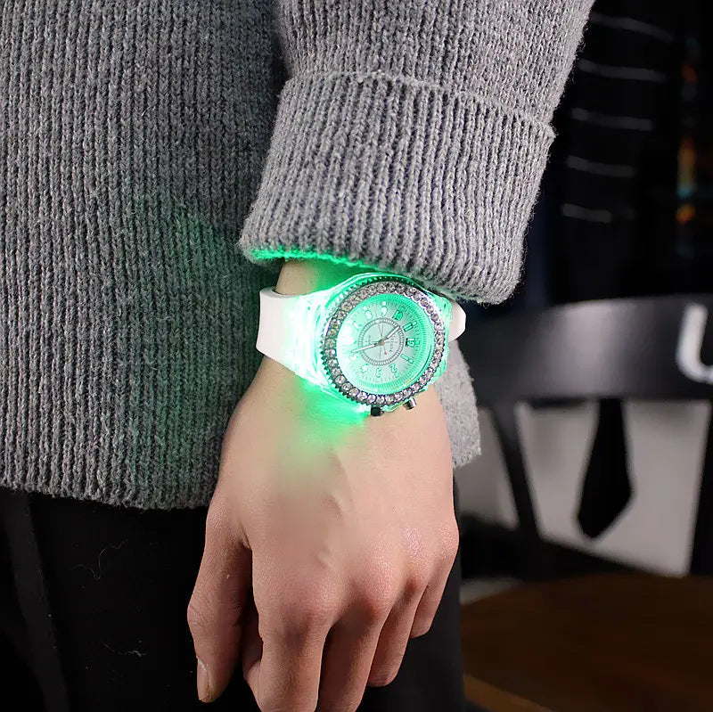 A led luminous silicone watch with a glowing green digital display a white silicone strap and a bezel encrusted with sparkling rhinestones.