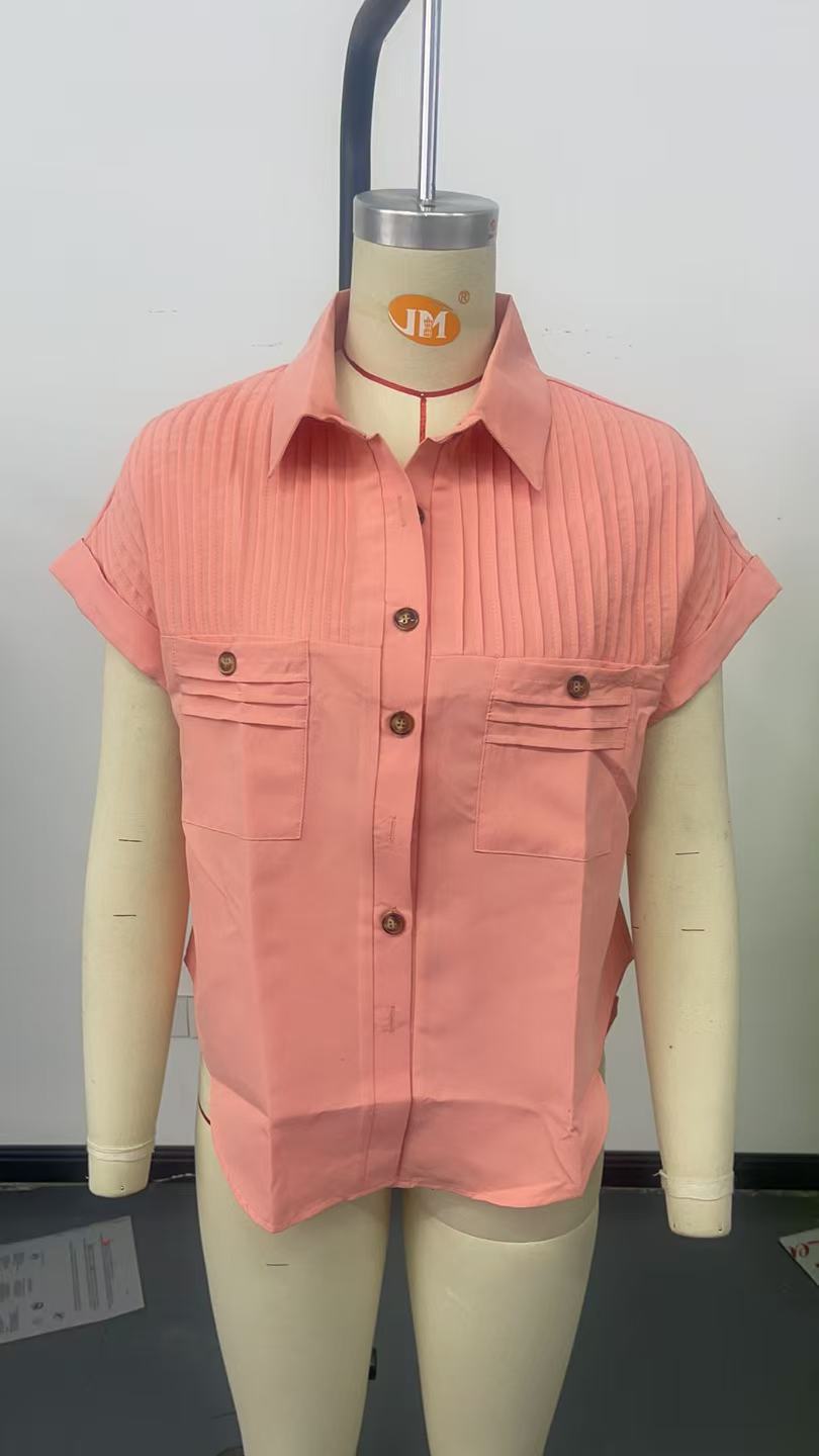 A coral-colored short sleeve button up blouse for women featuring vertical pleats and two front pockets.