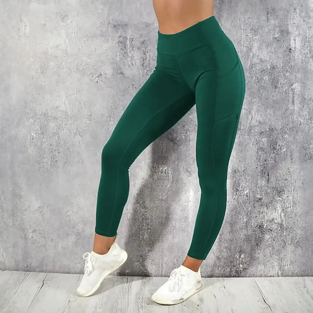 Deep green high waist booty lifting leggings with a sleek form fitting design and subtle side pockets.