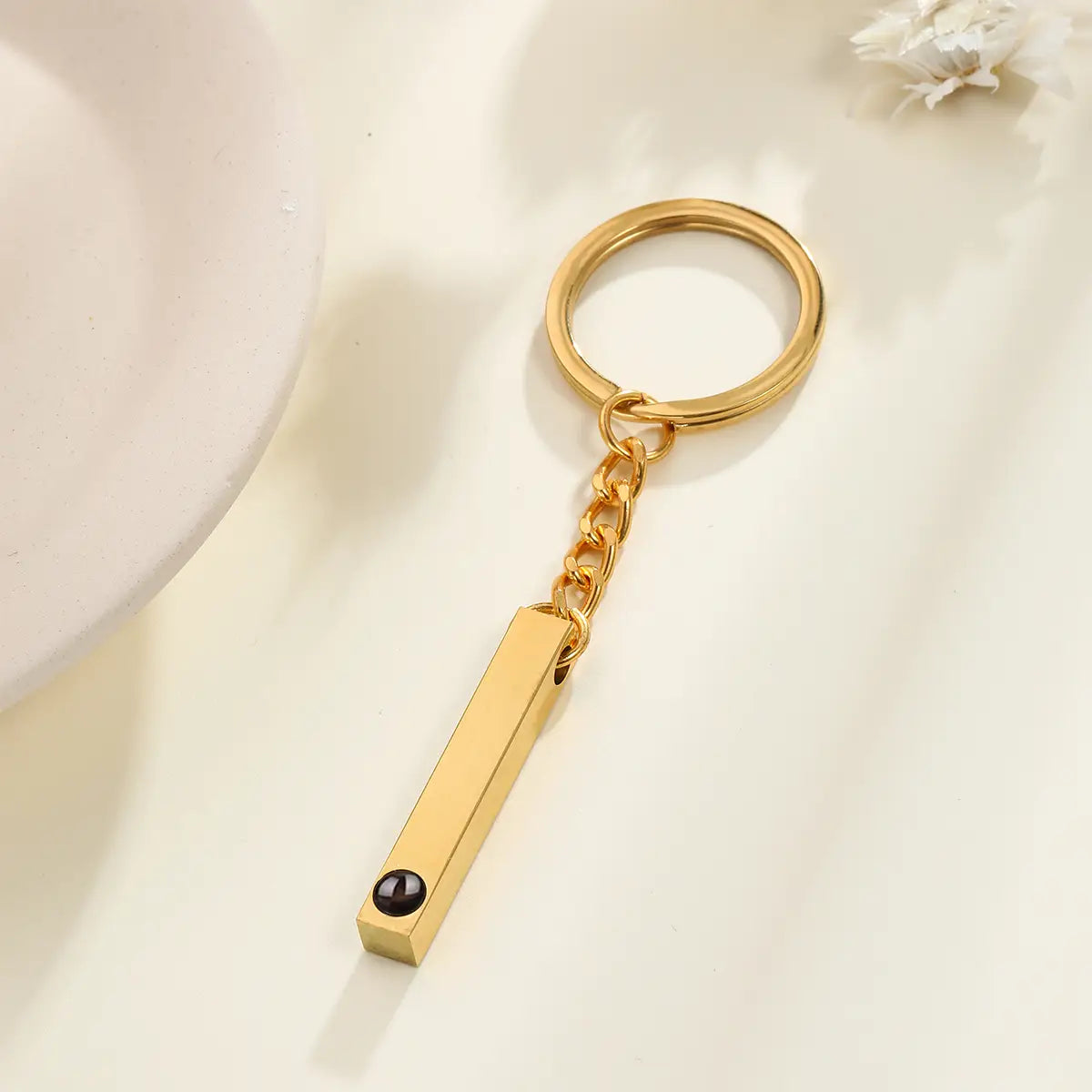 Gold-toned rectangular bar keychain with a small black gemstone at its base for custom photo projection personalized memorial gift.