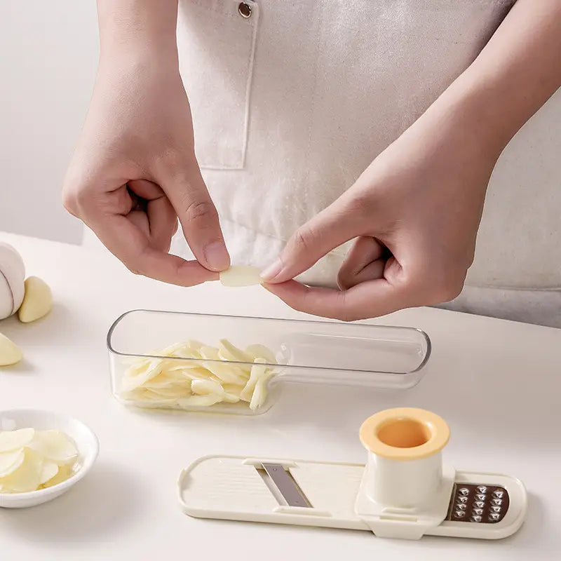 Moulin à ail en plastique blanc avec poignée beige et lame en acier inoxydable conçu pour un broyage précis de l’ail et le tranchage des légumes.
