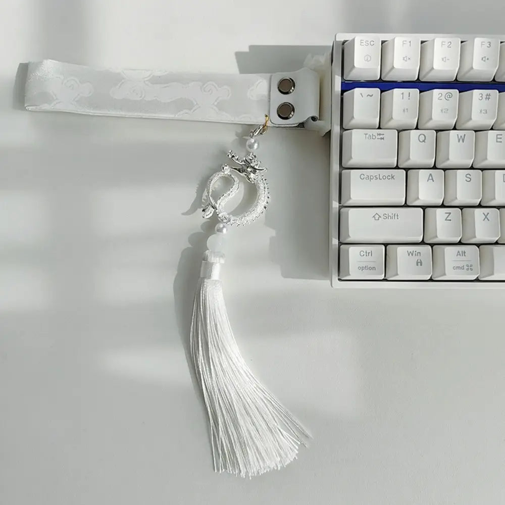 Sangle personnalisée pour le modèle Ribbon Dragon du clavier Wooting, comprenant une dragonne de poignet pour clavier sur le thème du dragon blanc, agrémentée d’éléments argentés, avec un pompon assorti.