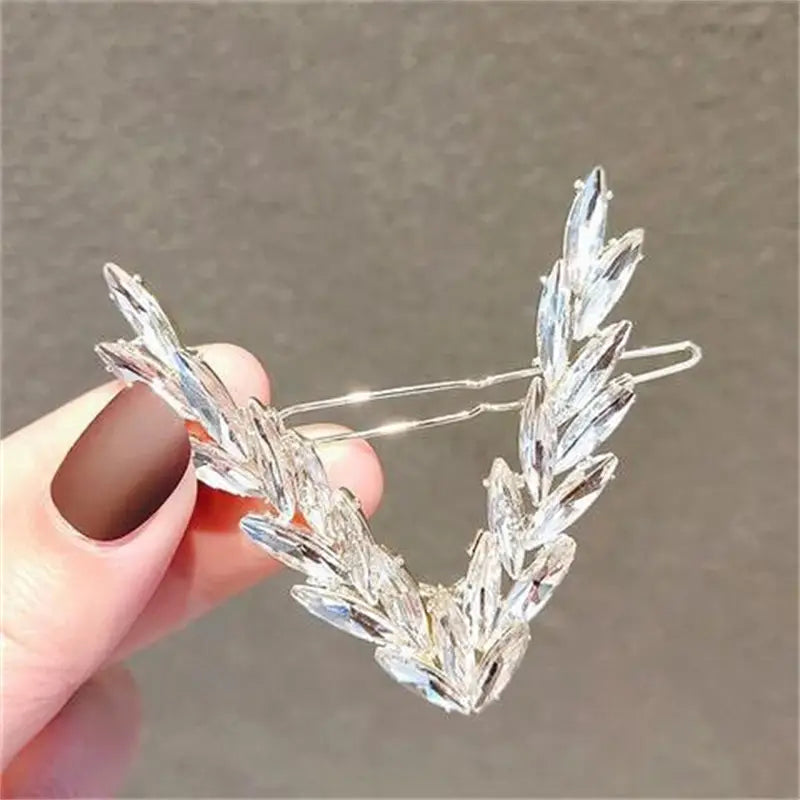 A delicate silver crystal v shape hair clip adorned with clear faceted crystal leaves arranged gracefully.
